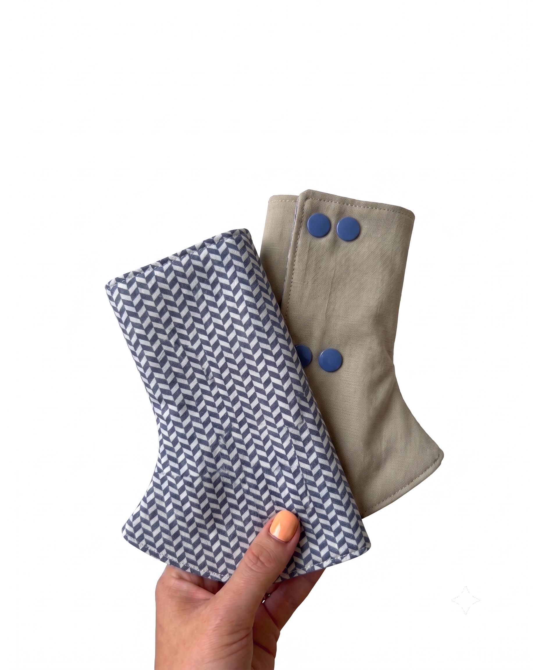 Two fabric suckpads for carrier, one with a zigzag pattern and the other beige with blue buttons, held by a hand on a white background.