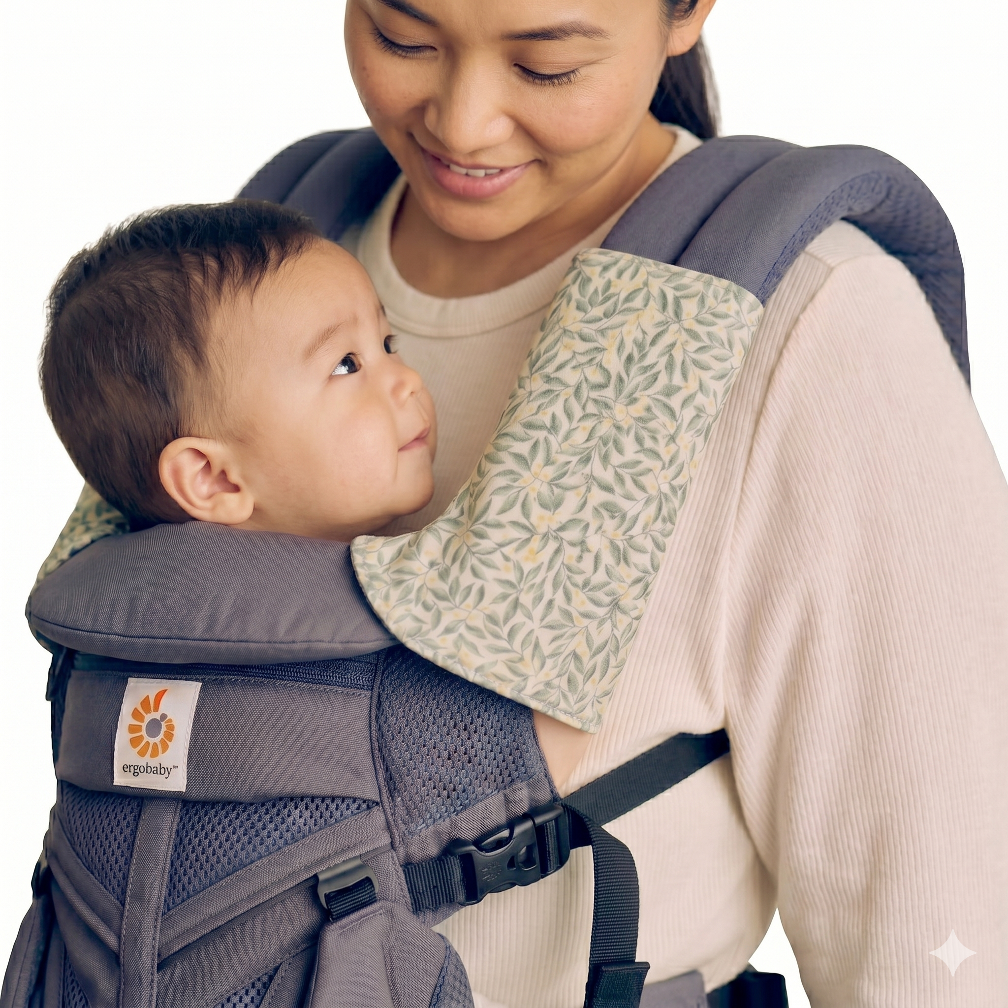 Woman carrying a baby in an Ergobaby carrier on a white background with green floral suck pads