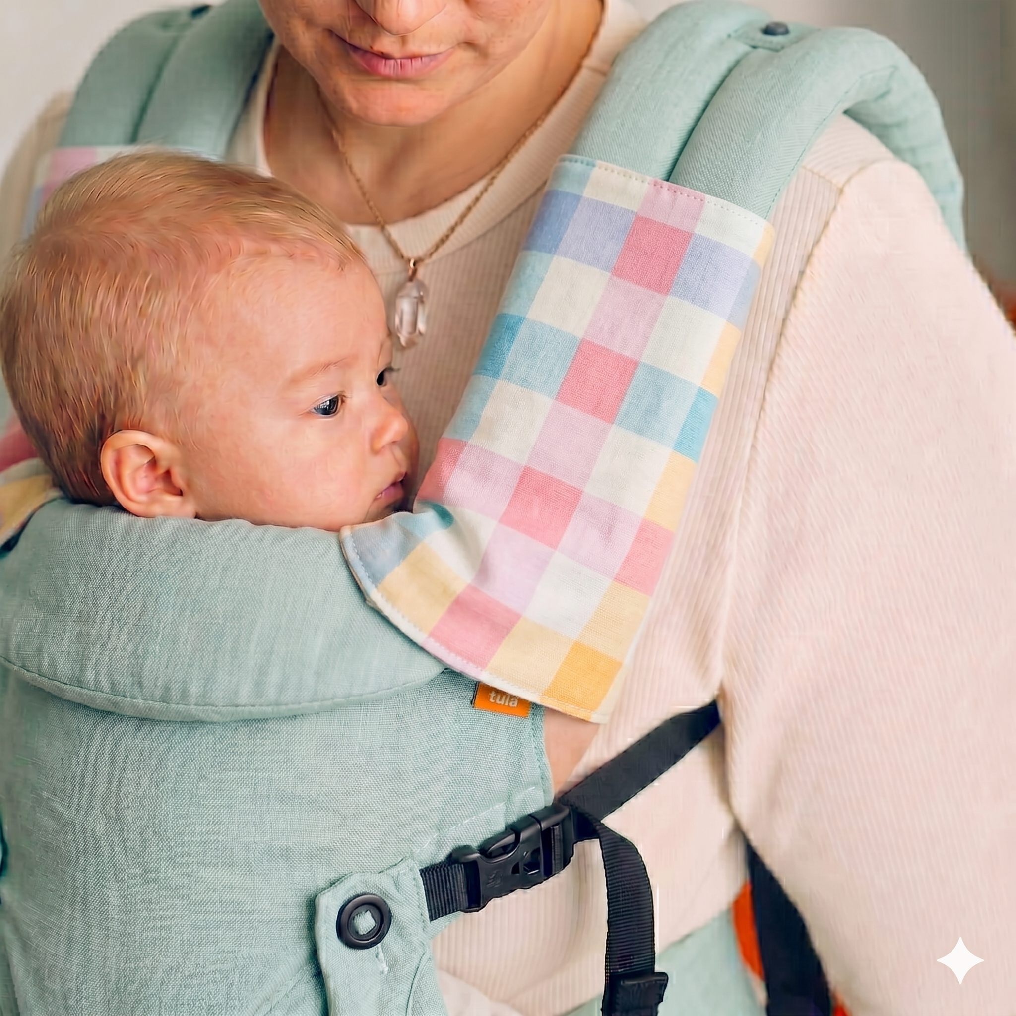 Baby in a baby carrier with a colorful suckapds for drool