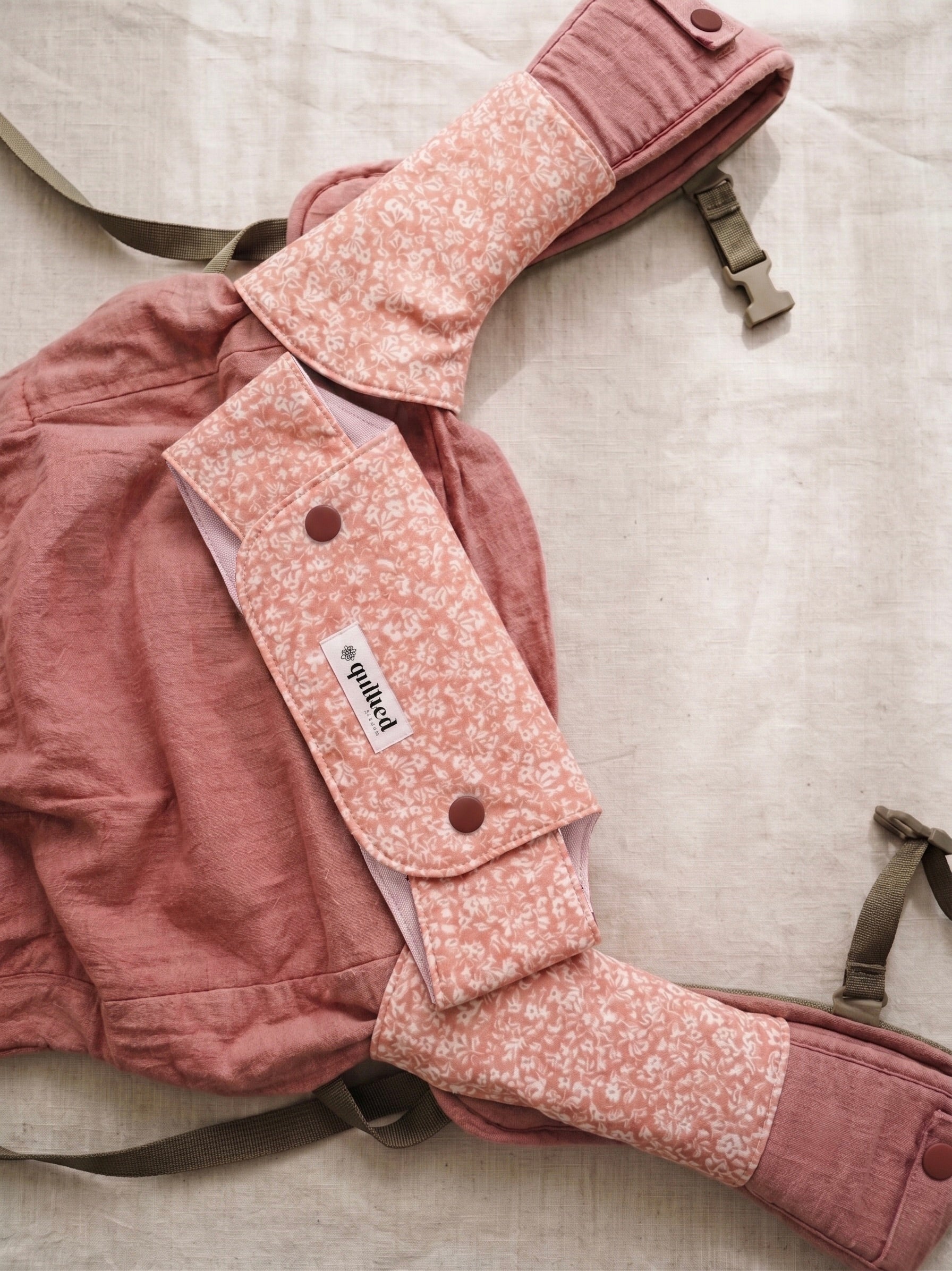 Pink baby carrier with floral pattern suckpads on a light background